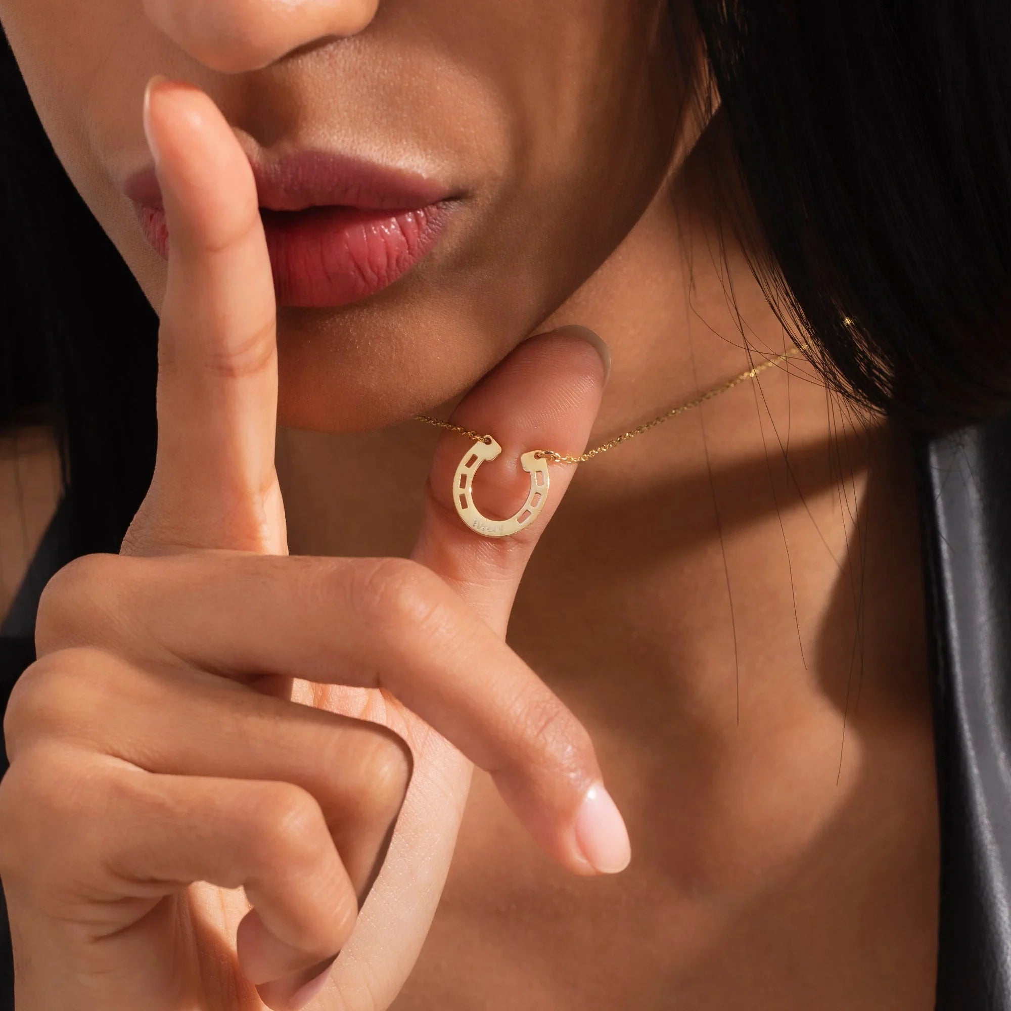 Close-up of a woman wearing a gold necklace with a personalized horseshoe pendant